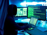 Un hacker delante de unas pantallas.