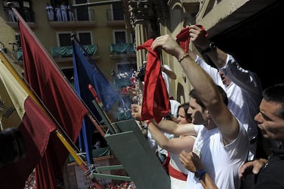 Javier Aranegui, miembro del Orfeón Pamplonés, y Chantal Estrade, nieta de uno de los fundadores de la peña La Veleta, que incorporó la indumentaria blanca y roja a las fiestas de San Fermín, comparten el lanzamiento del Chupinazo desde el balcón del Ayuntamiento de Pamplona.