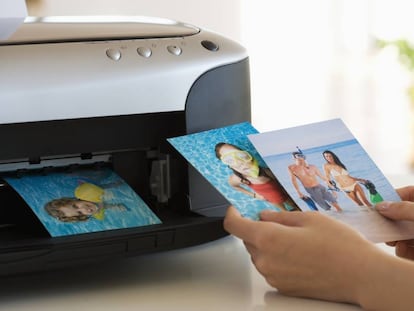 Una persona echa un vistazo a fotos impresas en color desde una impresora.