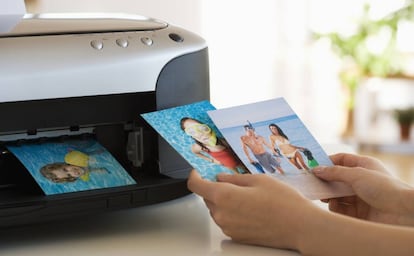 Una persona echa un vistazo a fotos impresas en color desde una impresora.
