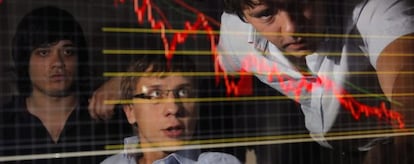 Empleados de una compañía de inversión en bolsa se muestran preocupados al contemplar un gráfico que detalla la tendencia a la baja de los valores bursátiles, en Moscú (Rusia).