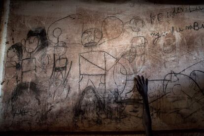 La mano de un joven refugiado del sur de Sudán se ve frente a una pared llena de dibujos y escritos que representan escenas de su casa, en un campo de refugiados para sudaneses del sur en Aru (República Democrática del Congo), el 12 de mayo de 2019. Un reciente aumento en la lucha entre las fuerzas del gobierno de Sudán del Sur y los grupos rebeldes a lo largo de la frontera de Sudán del Sur y la República Democrática del Congo ha provocado que miles de personas se refugien en este país desde principios de año.