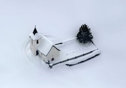 Vista aérea de la iglesia de Jenisberg, cerca de Davos, Suiza, cubierta totalmente de nieve.