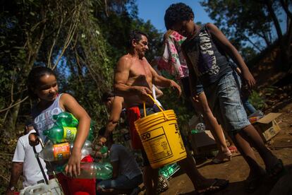 As crianças colaboram na captação de água na bica. Enquanto as mães carregam os galões, os pequenos se ocupam das garrafas menores ao voltar da escola.