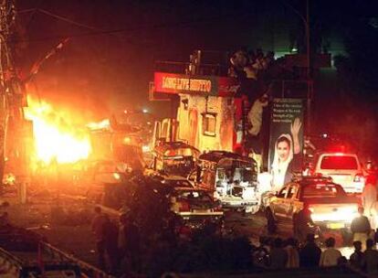 Un coche estalla en llamas junto al camión en el que viajaba Benazir Bhutto, tras el atentado de anoche en Karachi.