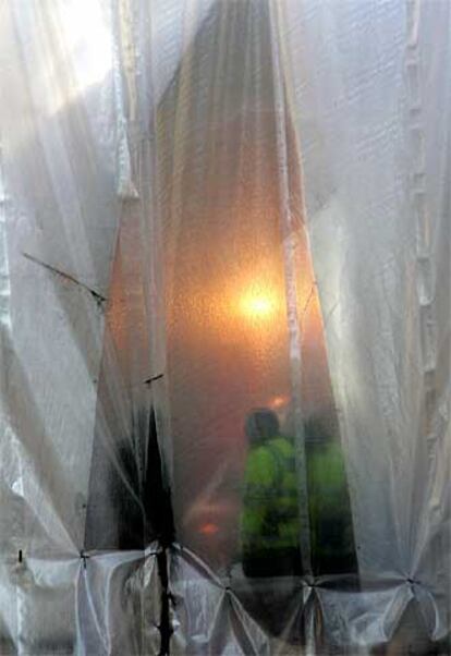 Un policía cierra la cortina utilizada para proteger de la vista el lugar donde el pasado 7 de julio estalló una bomba en un autobús. Según ha afirmado Scotland Yard, existen pruebas que confirman la muerte de uno de los terroristas suicidas durante los ataques.