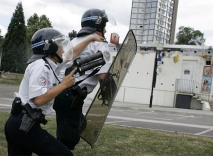 Dos policías protegen un centro comercial durante los disturbios del pasado viernes en Firminy.