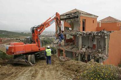 Una grúa derriba las viviendas construidas en zona verde.