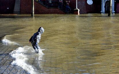 Un niño juega en el agua frente a un mercado inundado por la tormenta Herwart en Hambugo (Alemania).
