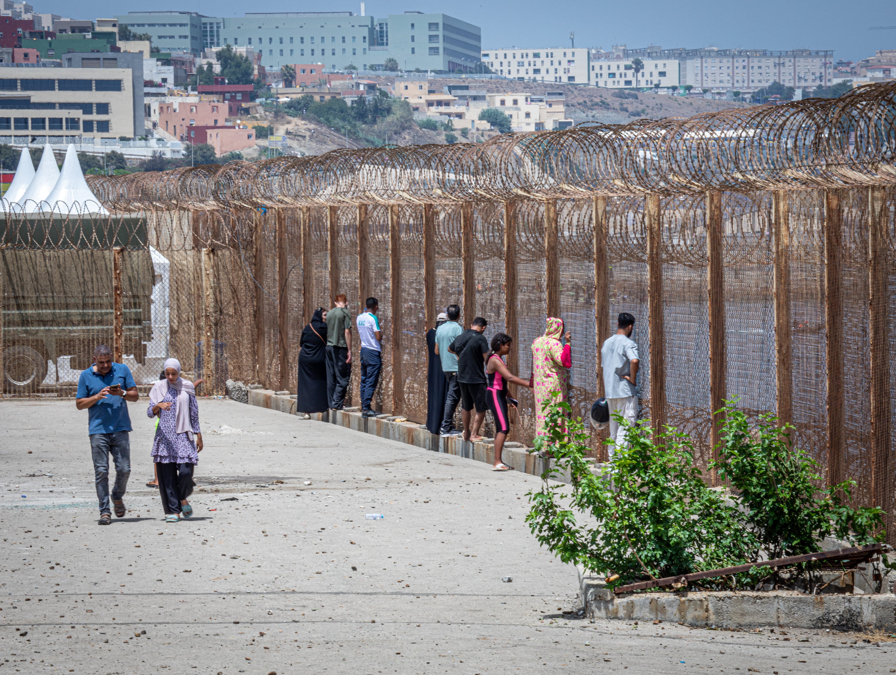 Familiares de jóvenes marroquíes que han cruzado a Ceuta sin haber vuelto aún esperar su retorno este sábado en la valla de la frontera de Castillejos.