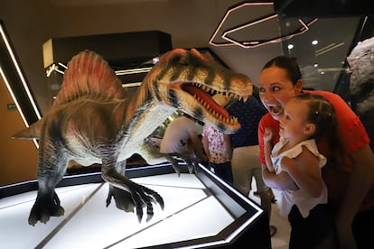 Los visitantes podrán explorar los diversos atractivos que se ofrecen en el museo a través de ‘mappings’, realidad aumentada y tabletas digitales para que diseñen su propio dinosaurio, entre otras experiencias. En la imagen, una mujer acerca a su hija a una de las figuras en tamaño real de un dinosaurio.