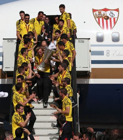 Rakitic baja del avión con la copa.