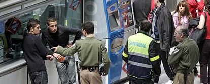 Un vigilante habla con dos jóvenes en las taquillas de una estación ante la mirada de otros dos compañeros.