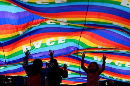 Tres niños juegan con una bandera gigante durante la protesta contra la guerra en Milán (Italia).