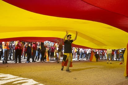 Un joven camina por debajo de una enorme bandera español.