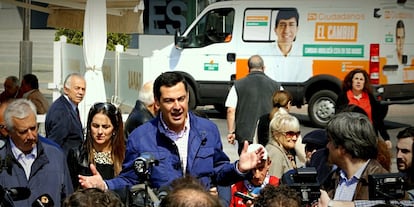 El candidado del Partido Popular a la Junta de Andalucía, Juan Manuel Moreno, da un discurso en la calle a la entrada del Mercado de Abastos de Almería, mientras pasa una furgoneta del candidato de Ciudadanos, el 15 de marzo de 2015.