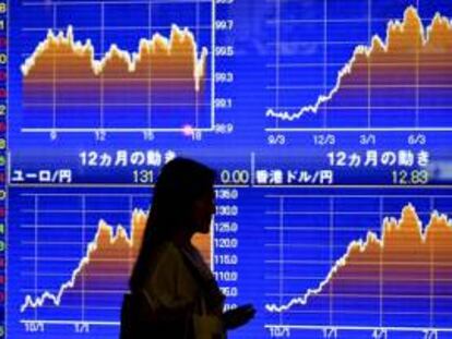 Una mujer pasa delante de una pantalla que muestra la evolución de la Bolsa de Tokio. EFE/Archivo