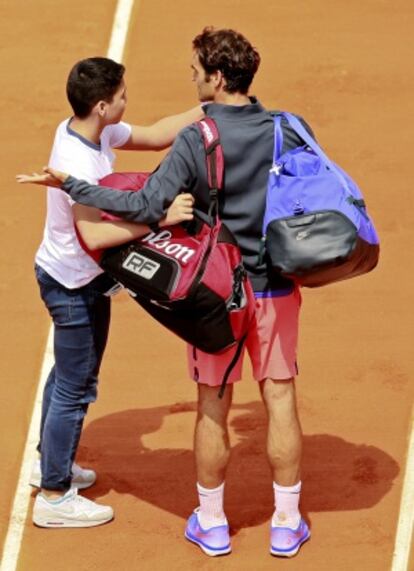 Un niño intenta sacarse una foto sobre la pista con Federer.