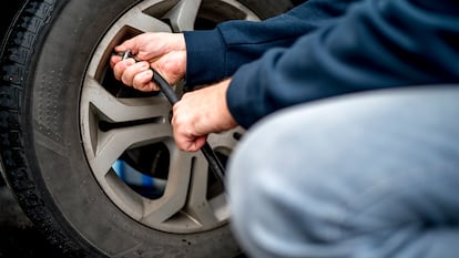 Un hombre inflando la rueda de su coche.