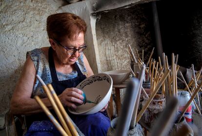 La artesana Dolores García trabaja la pintura de los barros antes del proceso de cocción en la alfarería de Ángel y Loli en Nijar, Almería.  