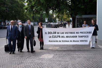 El psiquiatra Javier Criado (centro) llega a los juzgados de Sevilla este miércoles, recibido por una pancarta de la asociación de sus supuestas víctimas.