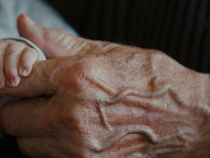 Un bebé agarra la mano de su abuelo.