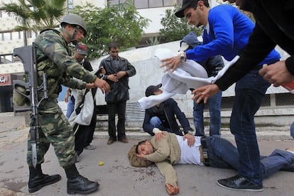 Un soldado contempla a un hombre herido de bala que yace en el suelo inconsciente después de que la zona fuera gaseada.