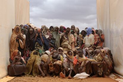 Refugiados somalíes en un campamento de Etiopía esperan entre dos tiendas para recibir alimento.