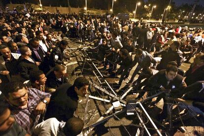 Unos manifestantes retiran la alambrada que protege el acceso al Palacio Presidencial en El Cairo.