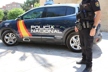 Imagen de archivo de un agente de la Policía Nacional junto a un coche patrulla.