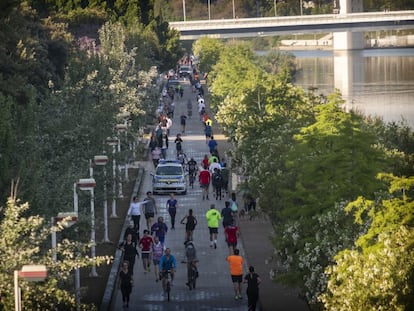 Un coche de la Policía Local de Sevilla circula entre cclistas, corredores y caminantes junto al río Guadalquivir en Sevilla, el 2 de mayo.