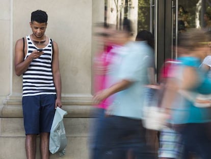 Unos j&oacute;venes consultan el m&oacute;vil en el Paseo de Gracia, en Barcelona