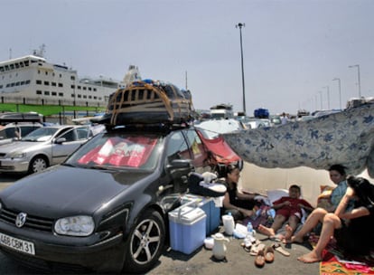 Una familia se protegía con un sombrajo junto a su coche, ayer, en el puerto de Alicante.