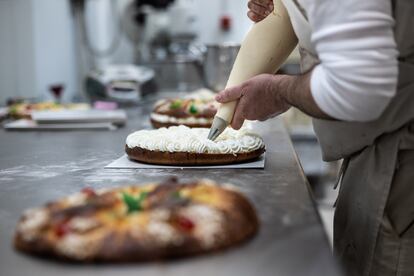 Un repostero rellena de nata uno de los roscones de reyes elaborados.