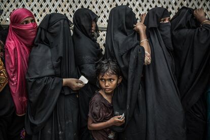 Halima y su madre esperan bajo la lluvia una distribución de comida en Jatmoli asentamiento improvisado de refugiados en Bangladés.