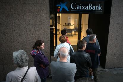 Un grupo de personas espera su turno en la entrada de una oficina bancaria en Barcelona.