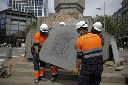 Varios trabajadores retiran un escudo del rey emérito de la plaza Cinc d'Oros de Barcelona, este sábado.