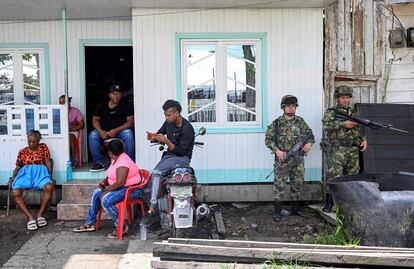 Soldados colombianos montan guardia mientras una familia escucha el discurso del presidente Gustavo Petro, en el municipio de Bocas de Satinga, el 13 de mayo de 2023.