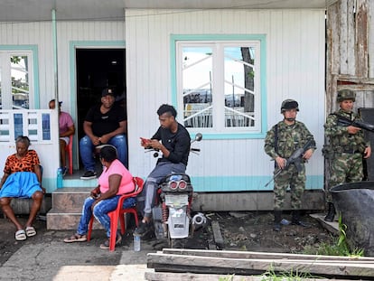 Soldados colombianos montan guardia mientras una familia escucha el discurso del presidente Gustavo Petro, en el municipio de Bocas de Satinga, el 13 de mayo de 2023.