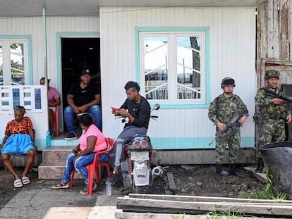 Soldados colombianos montan guardia mientras una familia escucha el discurso del presidente Gustavo Petro, en el municipio de Bocas de Satinga, el 13 de mayo de 2023.