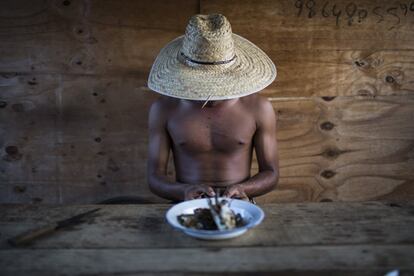 Rafael, un minero de diamantes se sienta a comer pescado en Areinha, durante un descanso.