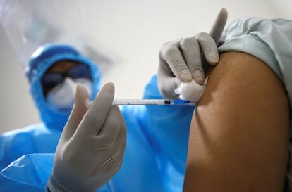 Un sanitario vacuna a otro profesional de la salud contra la covid-19 en Cali (Colombia).
