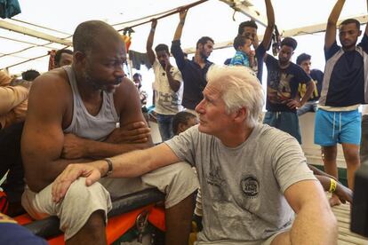 El actor Richard Gere, a la derecha, habla con un migrante a bordo del barco humanitario español mientras navega por el mar Mediterráneo.