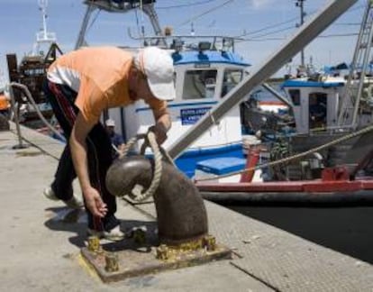 Un marinero manipula las amarras de una embarcación de arrastre en el puerto de Punta Umbría (Huelva).