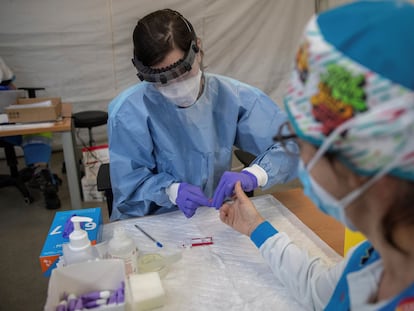 A health worker performs a fast coronavirus test on an emergency worker in Madrid.