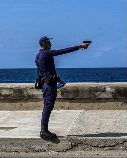 Un policía cubano usa su arma para disparar multas por exceso de velocidad a los conductores del Malecón en La Habana, Cuba, una de las muy pocas ocasiones en que se usan armas en este país.