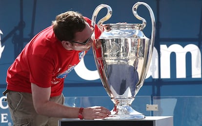Un aficionado del Atlético de Madrid besa la Copa de la Liga de Campeones que se expone en Lisboa.