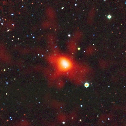 Gigantesco y lejano cúmulo de galaxias con cientos o hasta miles de galaxias ligadas por la atracción gravitatoria, tal y como era cuando el universo tenía tan sólo un tercio de su edad actual. Es una imagen con datos de varios telescopios. Las observaciones de rayos X del telescopio <i>XMM-Newton</i> revelan el gas muy caliente que rellena el cúmulo -la gran mancha naranja difusa-; las galaxias, observadas en luz visible e infrarroja por el telescopio <i>VLT,</i> son los pequeños objetos rojos y brillantes.