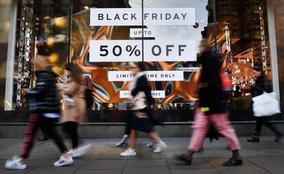 Varias personas caminan junto a un escaparate que ofrece descuentos por el 'Black Friday' en Londres (Reino Unido).