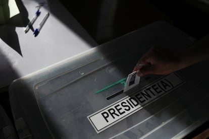 Una persona deposita su voto en una urna en un colegio electoral durante las elecciones generales.